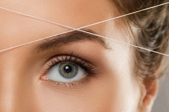 Close-up,Of,Female,Eye,With,A,Thread.,Eyebrow,Threading,-